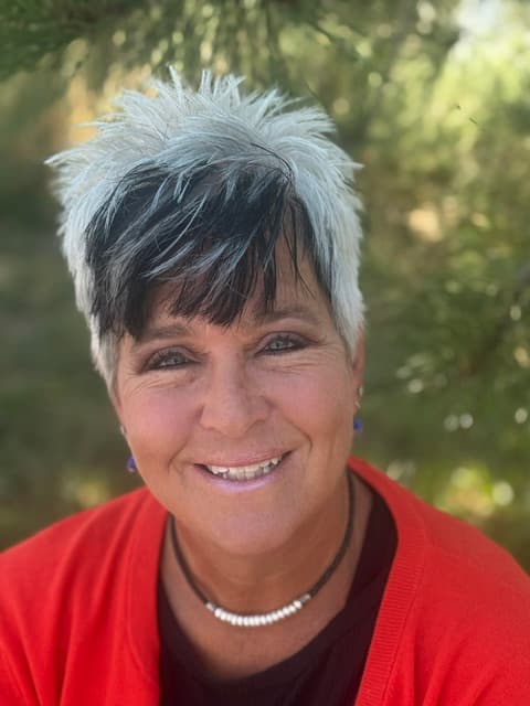 Portrait of a staff member in a red cardigan outdoors.