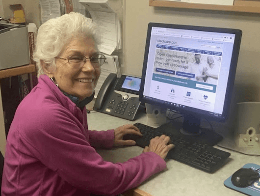A volunteer counselor at a computer showing the Medicare website.