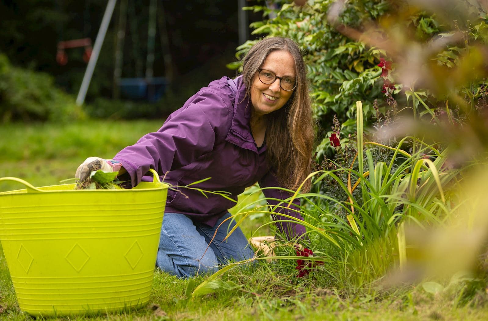 A volunteer kneeling to weed a garden bed.